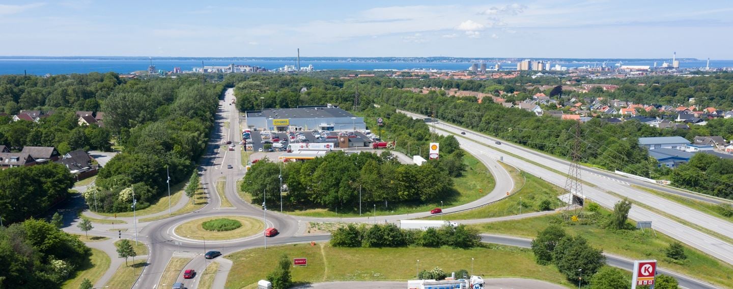 Bilden är tagen från ovan och visar huslängor med grönt runtomkring. Husen är vita med svarta tak