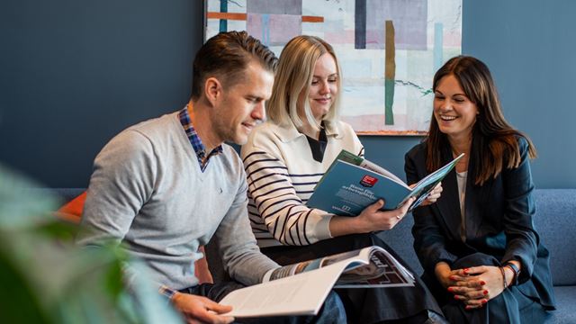 Wihlborgspersonal som sitter i ett rum med mörkblåa väggar och läser