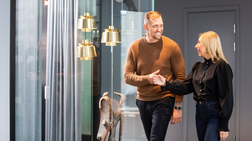 två personer går i en korridor och skakar samtidigt hand.