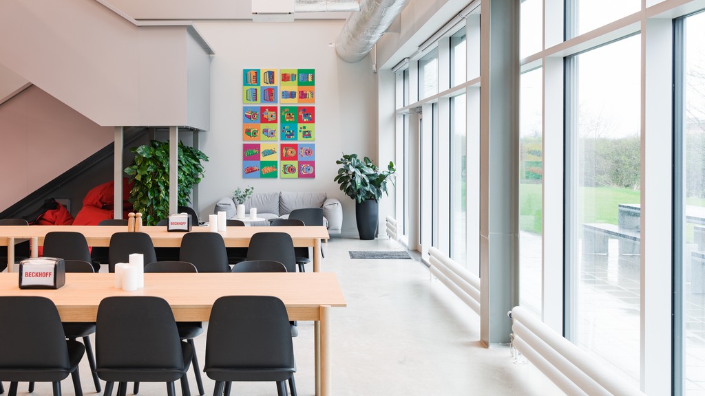 Lunchrum med långbord och stora fönster med grönska utanför