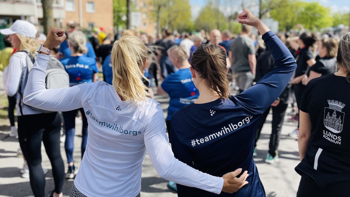 Två kvinnor som precis spungit ett lopp och höjer händerna i en segergest