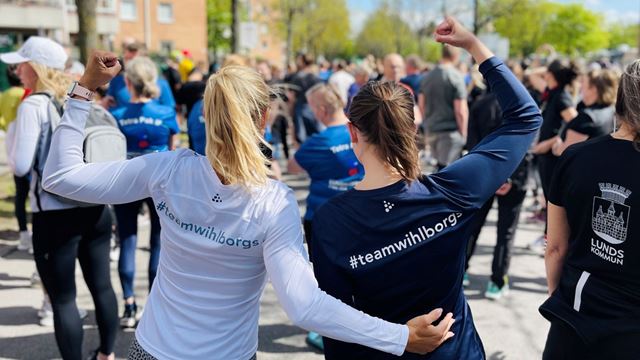 Två kvinnor som precis spungit ett lopp och höjer händerna i en segergest