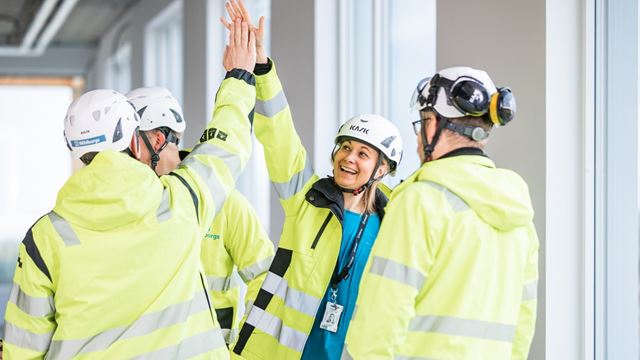 Flera personer på en byggarbetsplats gör en high five