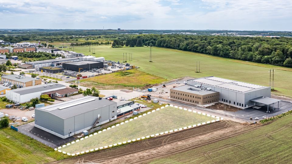 Illustration av en lagerlokal i rostfärg med staket som omgårdar området.