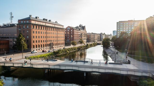 Fastigheten Sparven 15 med rött tegel och en kanal framför, där det är en person som paddlar.
