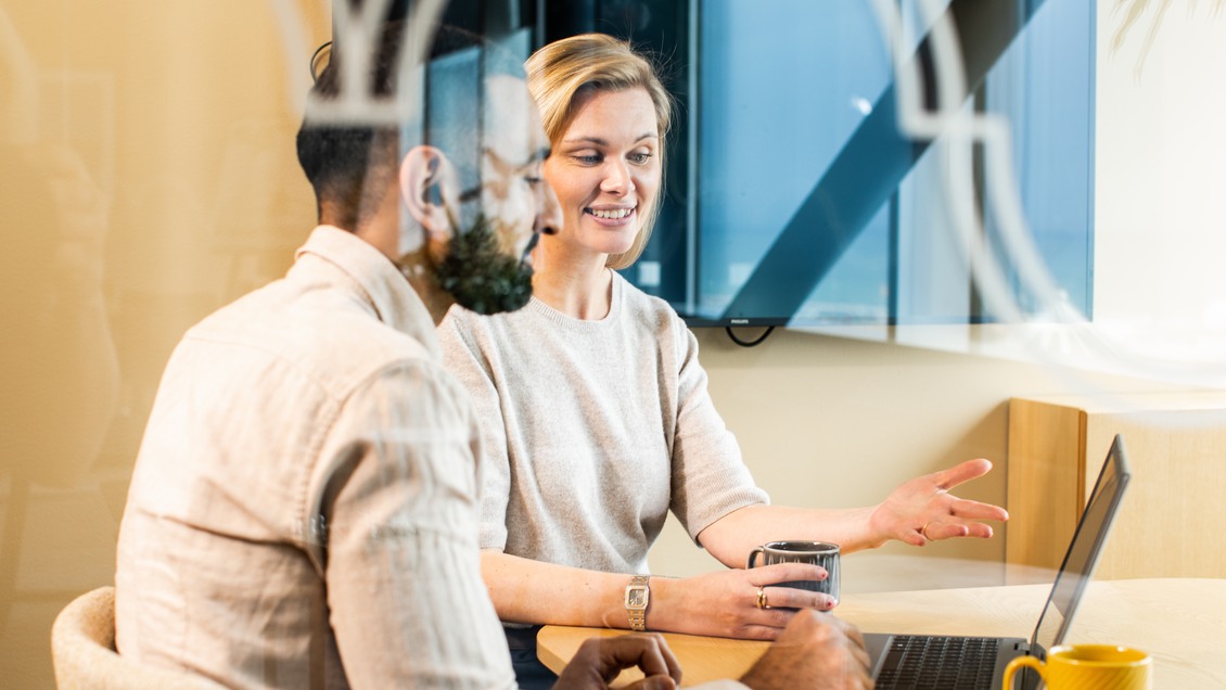 Två kollegor sitter vid datorn och pratar 