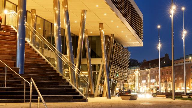 Bilden visar hotellets trappuppgång på kvällen. Hotellet lyser varmt och man ser staden i bakgrunden