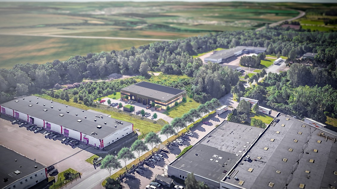 Bilden är tagen ovanifrån och visar längor av hus i en höstig miljö. Vita hus med svarta tak