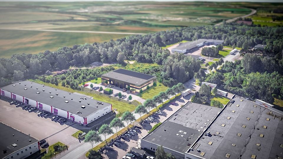 Bilden är tagen ovanifrån och visar längor av hus i en höstig miljö. Vita hus med svarta tak