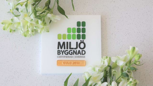 A logo of Miljöbyggnad Guld on a wall in a building. 