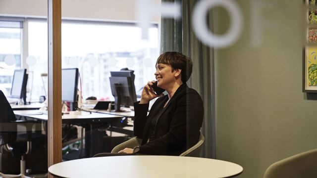 A woman talking on the phone in a conference room.