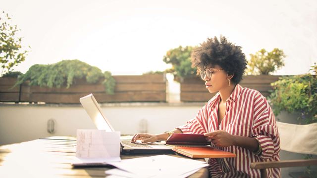 Kvinna som arbetar på en takterass i solen.