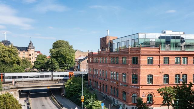 Ett tåg passerar bakom fastigheten Armaturen i centrala Lund.