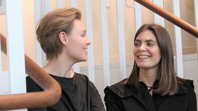 Traineerna Frida och Emilia sitter i en trappa.