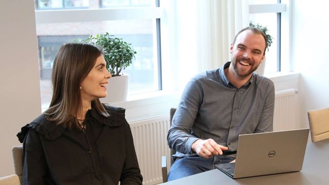 Traineerna Emilia och Erik sitter vid ett konferensbord.