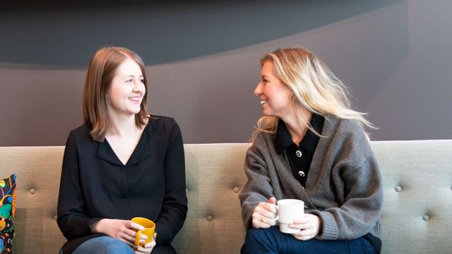 Praktikanterna Malin och Felicia sitter i en soffa och pratar.