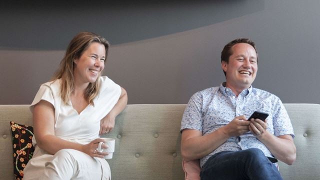 En man och en kvinna som sitter i en soffa och skrattar.