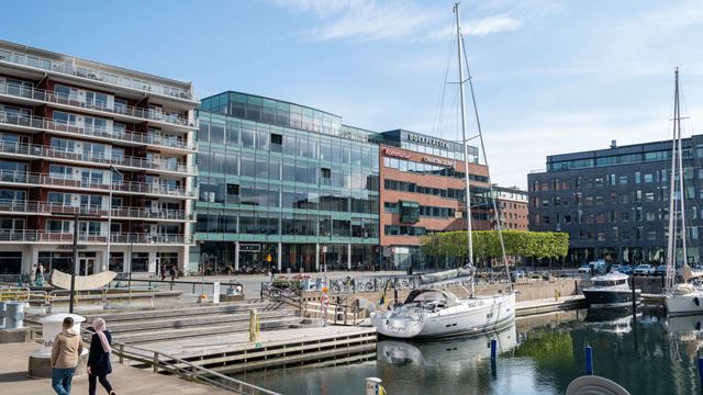 Två kvinnor som promenerar vid Dockan i Malmö. En segelbåt och kontorshus i bakgrunden.