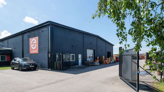 Bronsdolken 18, industrilokal med svart fasad, grindar i förgrunden.