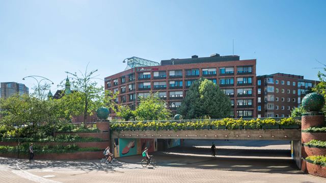 En cykeltunnel i förgrunden till den röda tegelfastigheten Uven i Malmö.