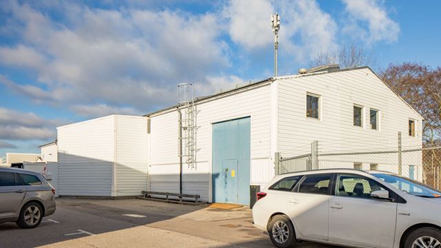 Vit industribyggnad med lastport och stängsel, Balken 7 i Limhamn,