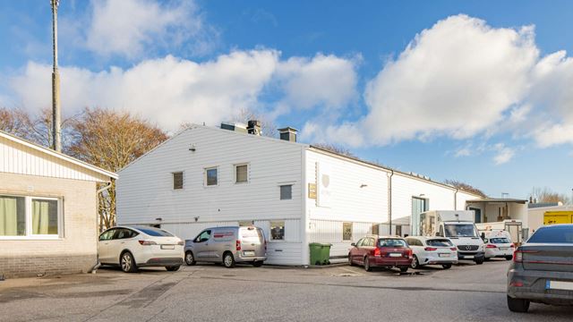 Vit industrilokal i Limhamn med parkeringsytor utanför, Balken 7.